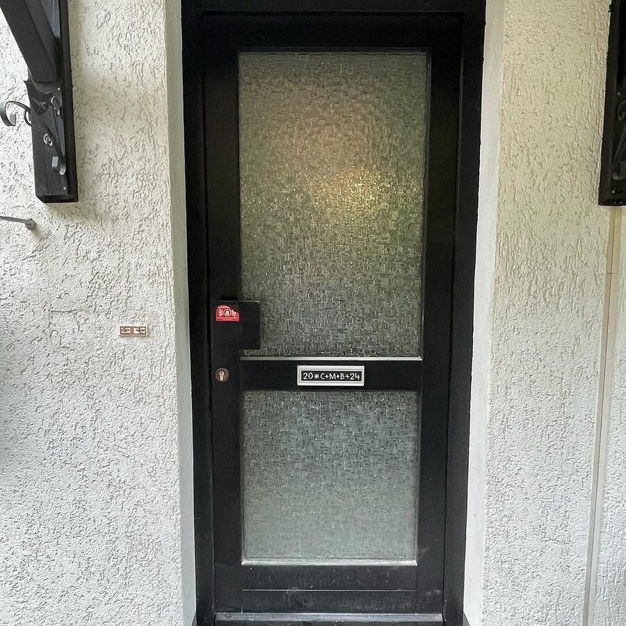 Schwarze Haustür mit Milchglas an einem hellen Wohnhaus