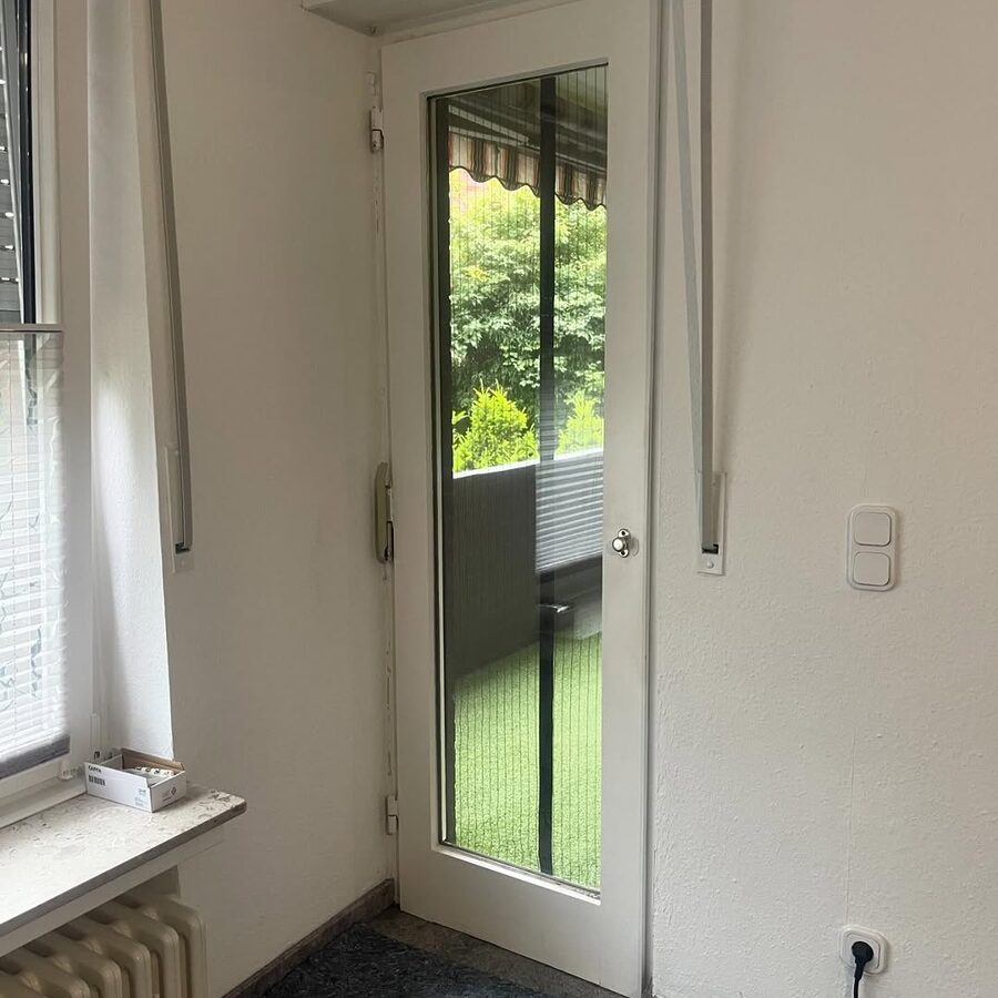Neue weiße Balkontür von innen mit Blick in den Garten